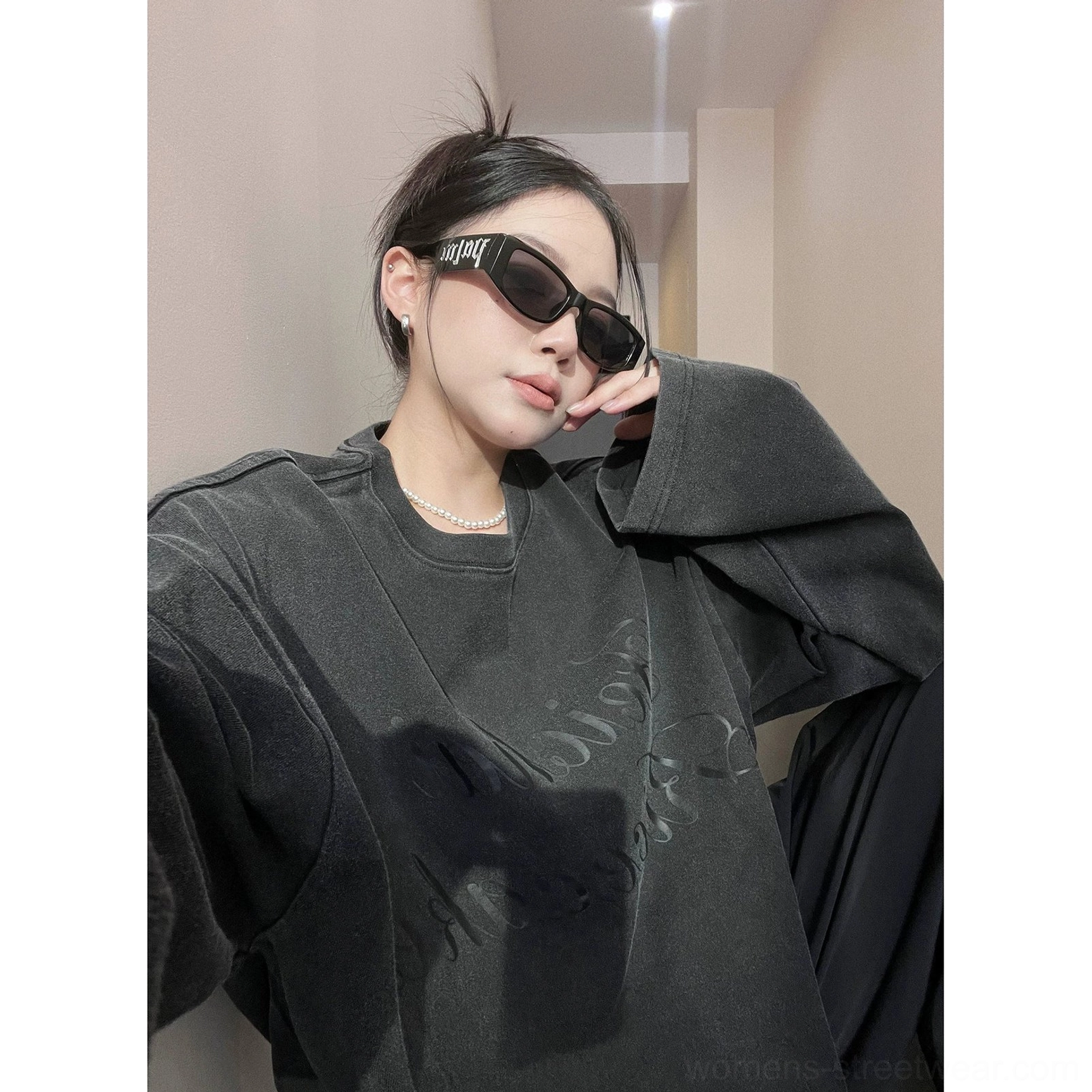 Close-up portrait of a woman in a washed black oversized fleece crewneck sweatshirt with tonal cursive print and vintage texture