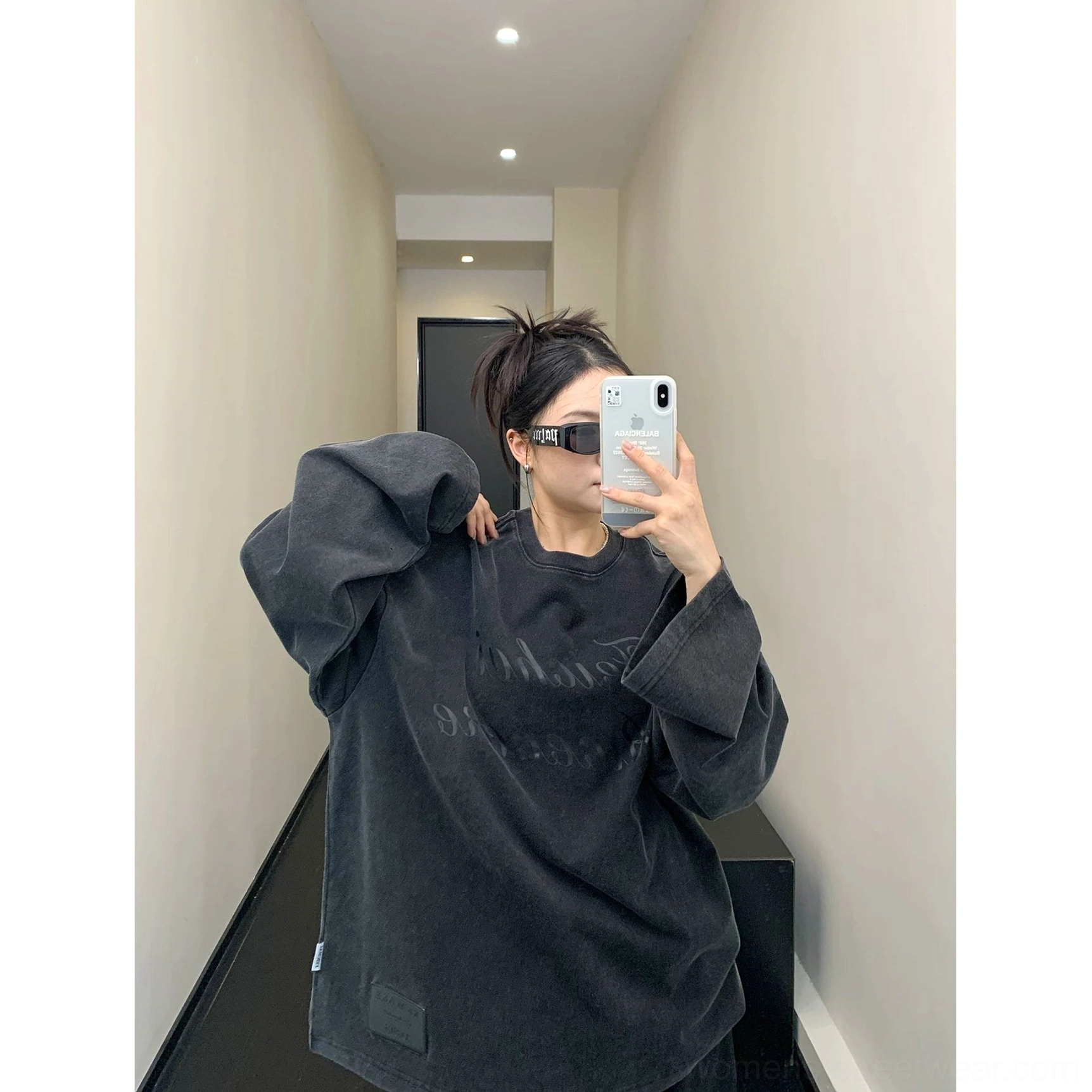 Front styling view of a woman wearing a washed black oversized script sweatshirt with relaxed proportions and small hem label