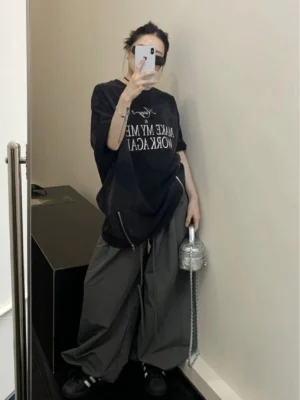 Mirror outfit view of washed black oversized graphic slogan T-shirt paired with grey wide-leg cargo pants