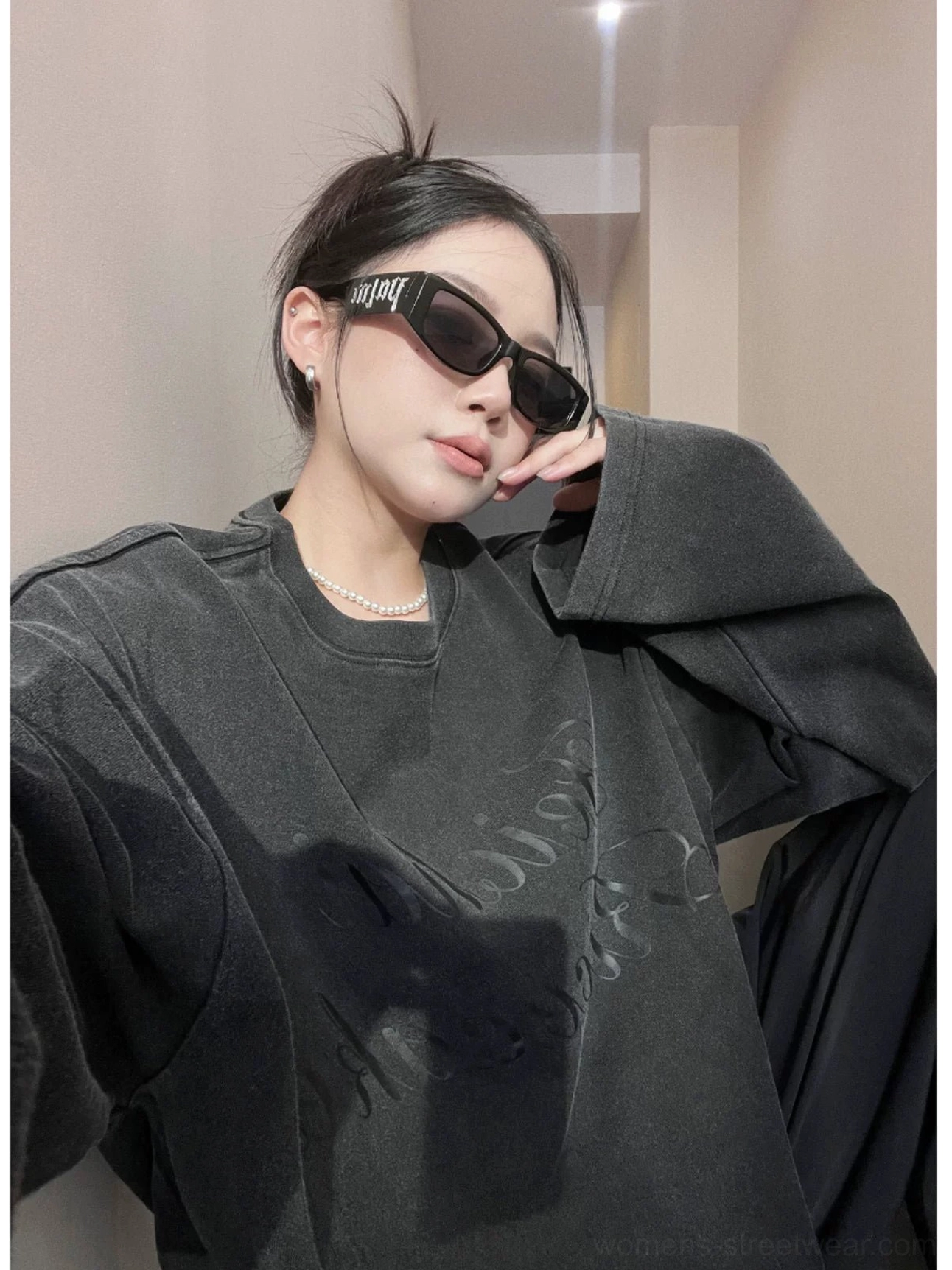 Close-up portrait of a woman wearing a vintage washed black oversized streetwear sweatshirt with ribbed crew neck and raised cursive lettering