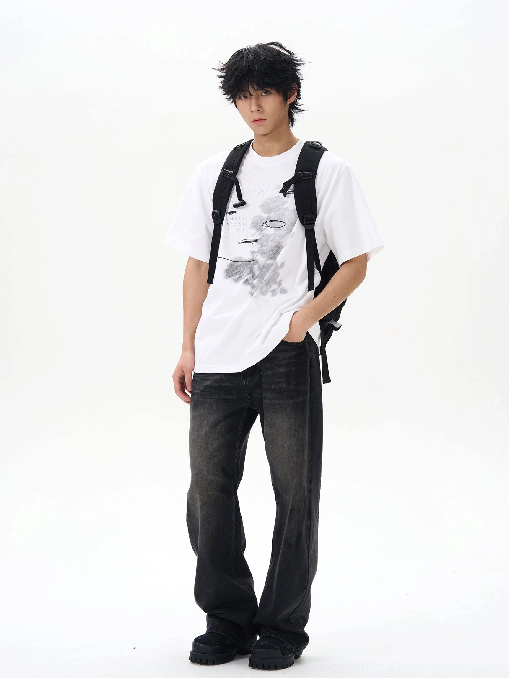 Side view of washed black straight loose jeans worn with a graphic tee and backpack, showing clean denim seams and relaxed silhouette