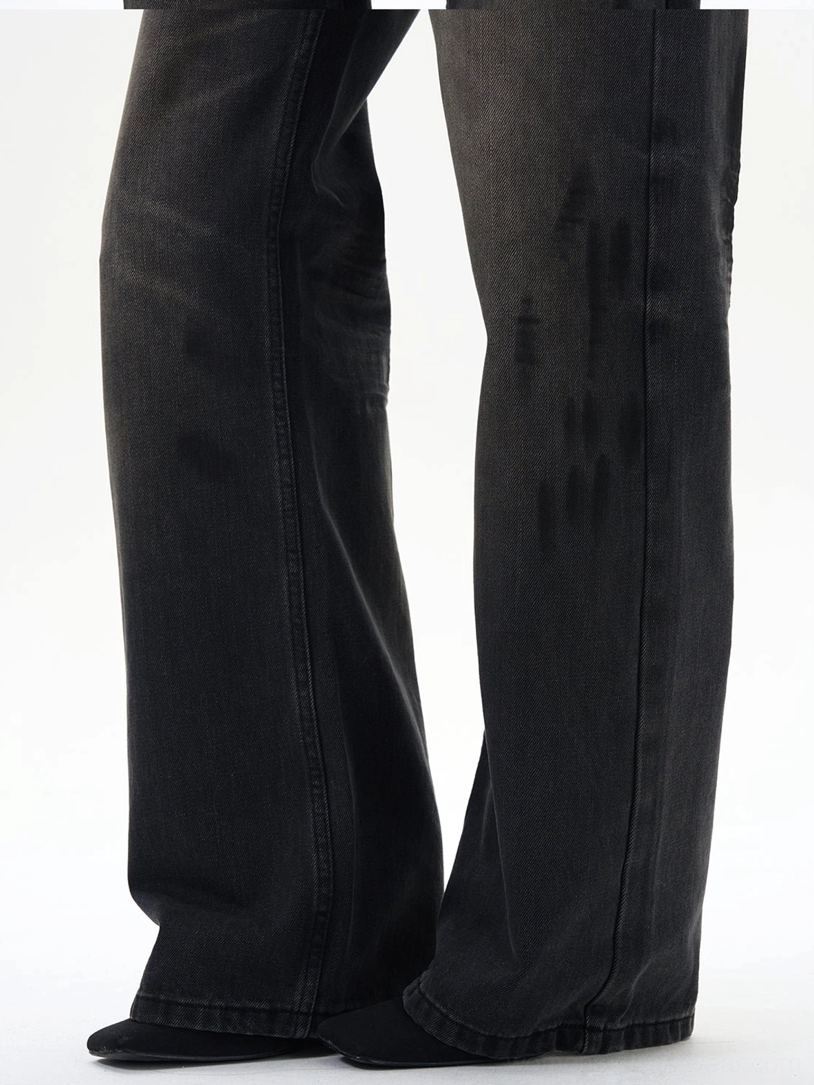 Close-up of washed black straight loose jeans hems showing faded wash streaks, deep black denim color, and wide straight-leg opening