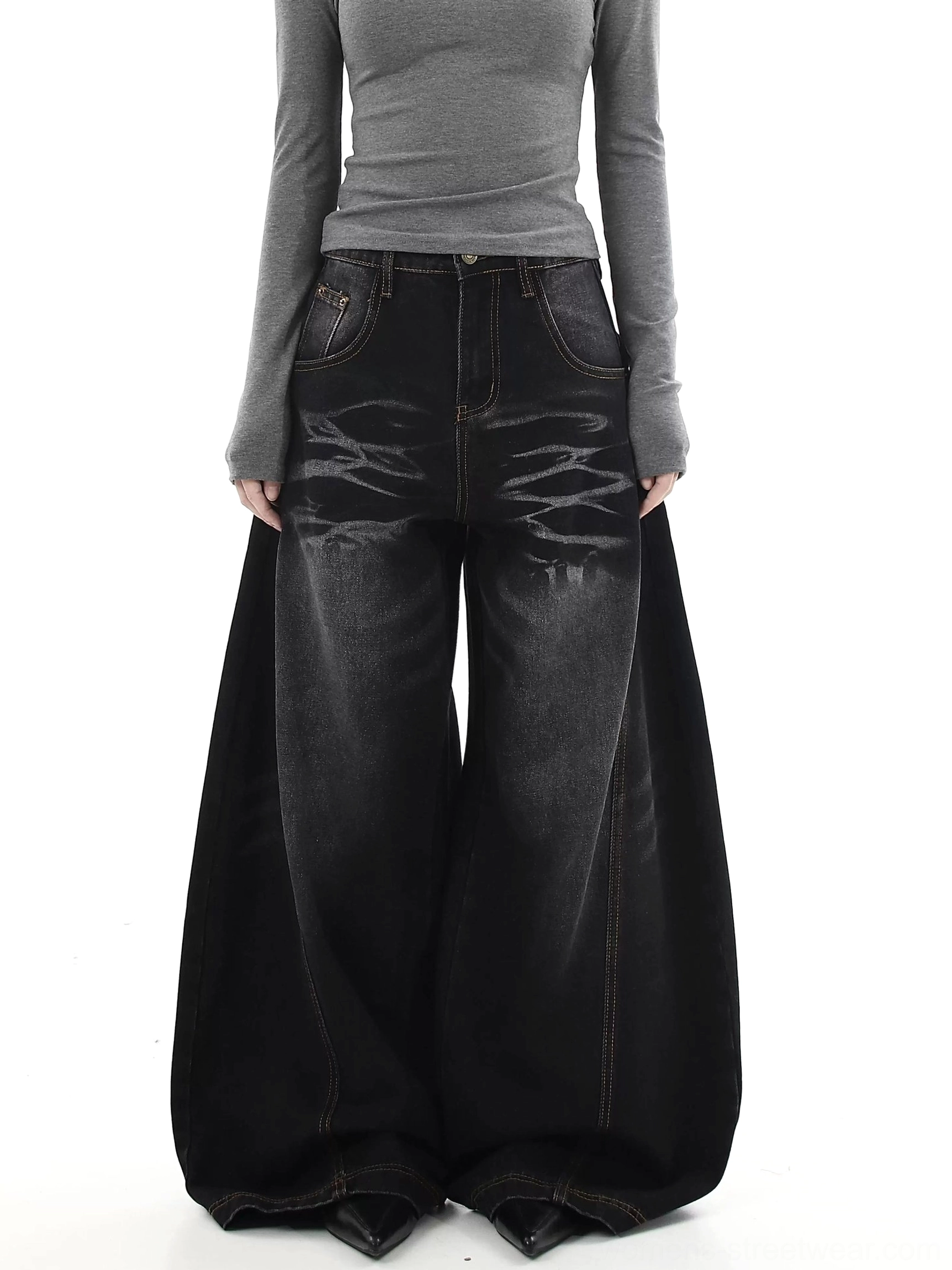 Female model wearing washed black ultra-wide flare jeans with tiger stripe fading and contrast stitching in a modern streetwear outfit