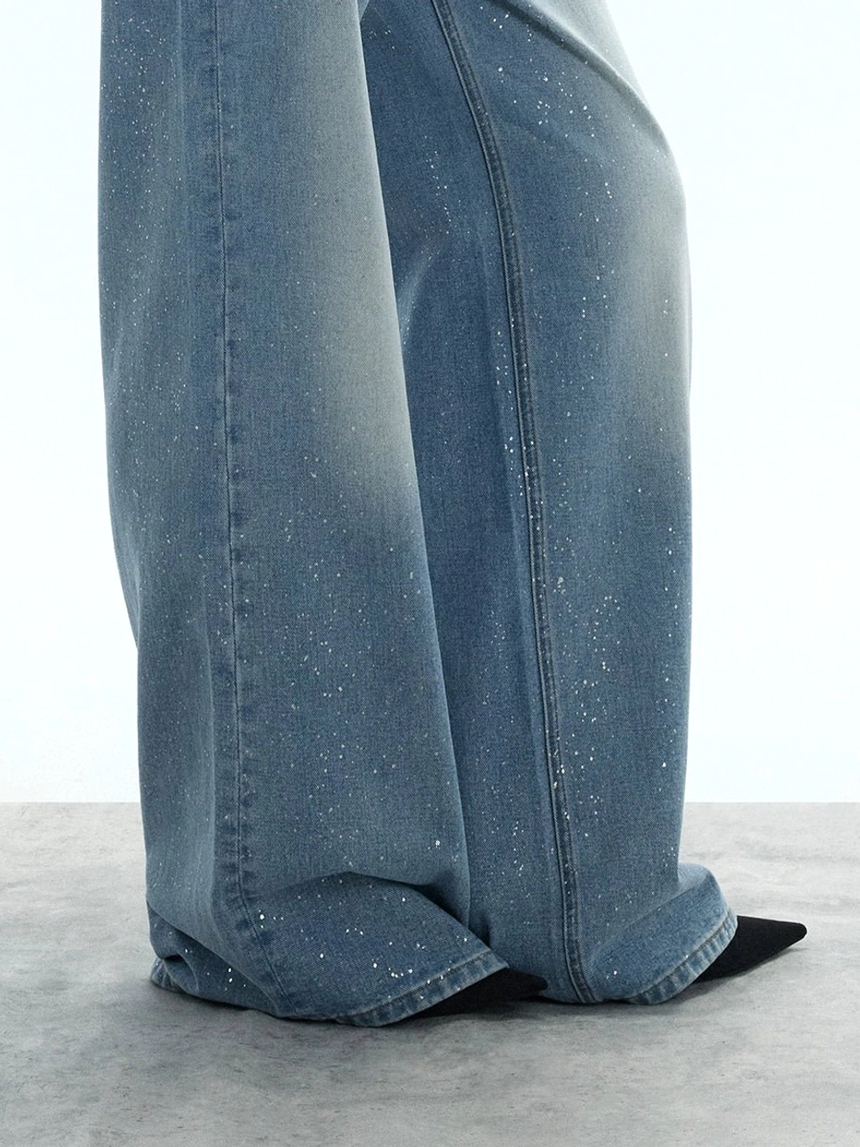 Close-up of the wide hem on washed blue glitter jeans showing the soft faded denim and delicate sparkling flecks