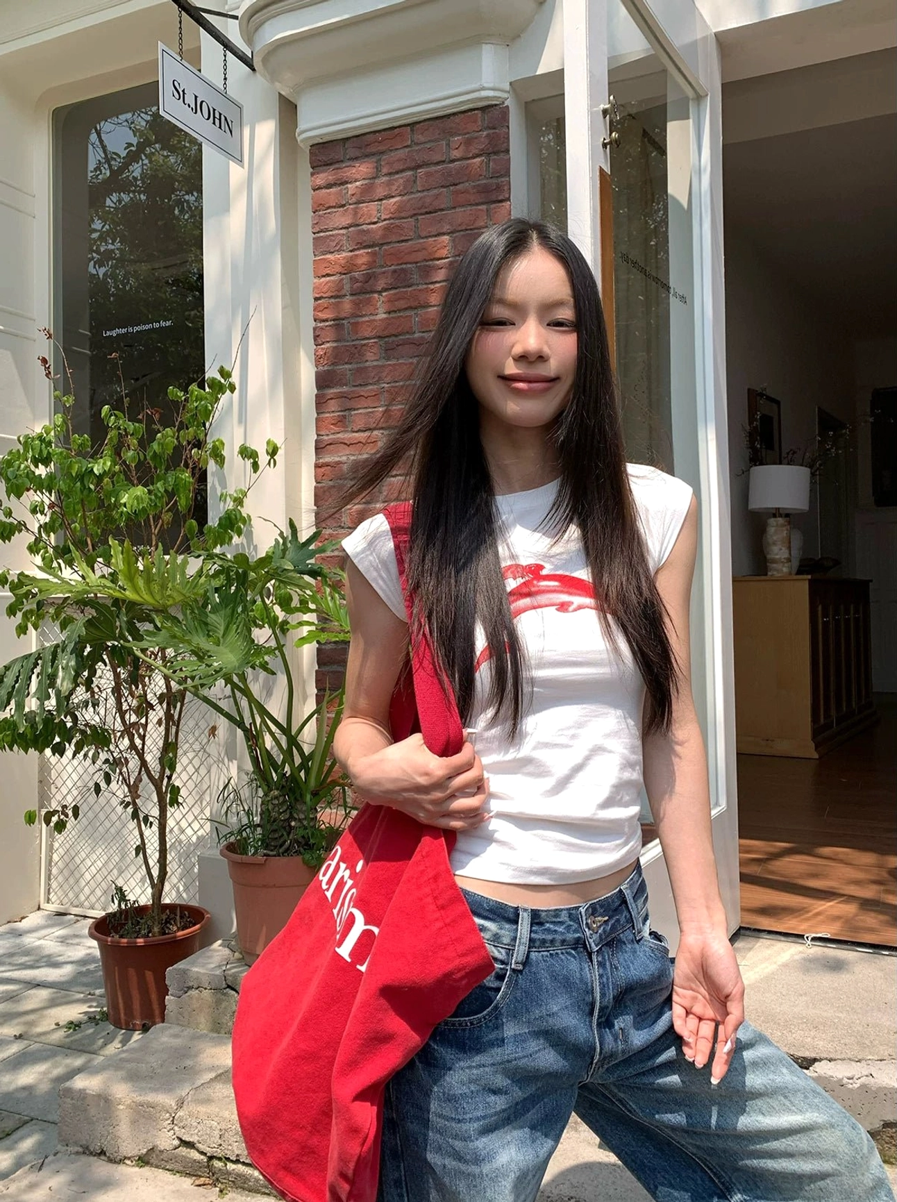Washed blue wide-leg jeans with low-rise waist styled beside a doorway with a printed red canvas tote