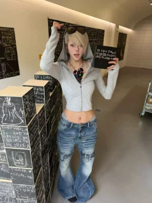 Front view of washed blue Y2K slogan flare jeans with low rise fit, bold leg graphics, and oversized streetwear silhouette