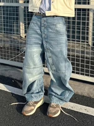 Model wearing washed brown retro trail runner sneakers with a cropped yellow jacket and baggy light wash jeans