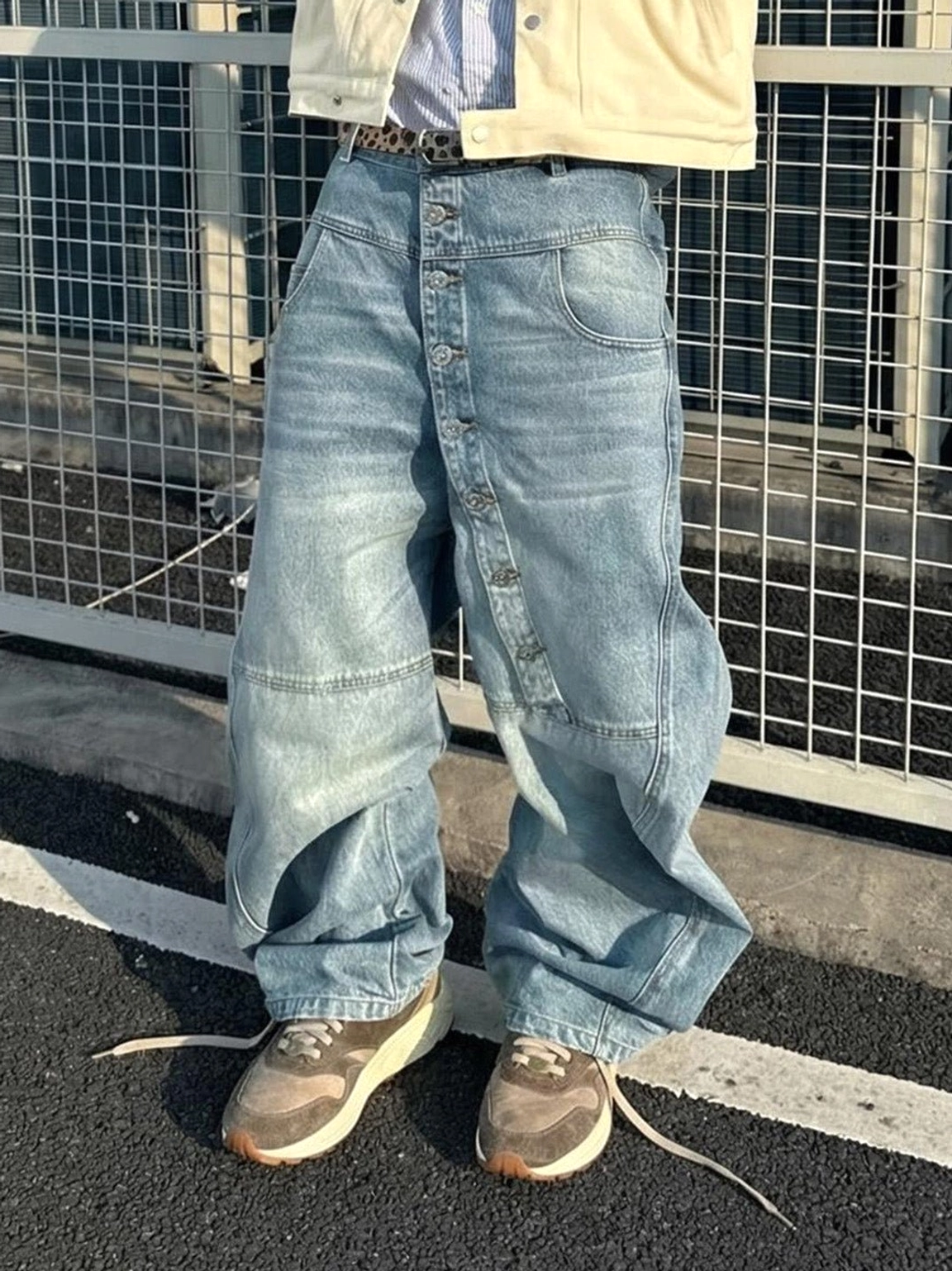 Model wearing washed brown retro trail runner sneakers with a cropped yellow jacket and baggy light wash jeans