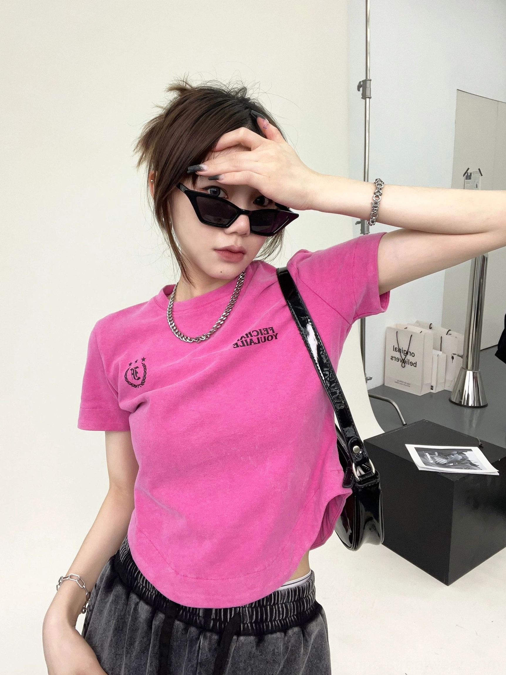 Hot pink washed collegiate logo curved hem streetwear t-shirt side view with silver jewelry