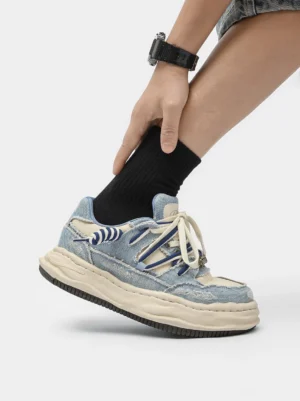 On-foot side view of washed denim dual-lace platform streetwear sneakers styled with black crew socks