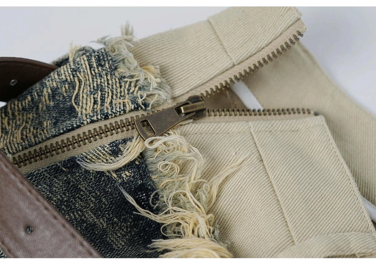 Close-up detail of the washed denim mini skirt zipper fly, metal hardware, frayed trim, and contrasting khaki inner fabric