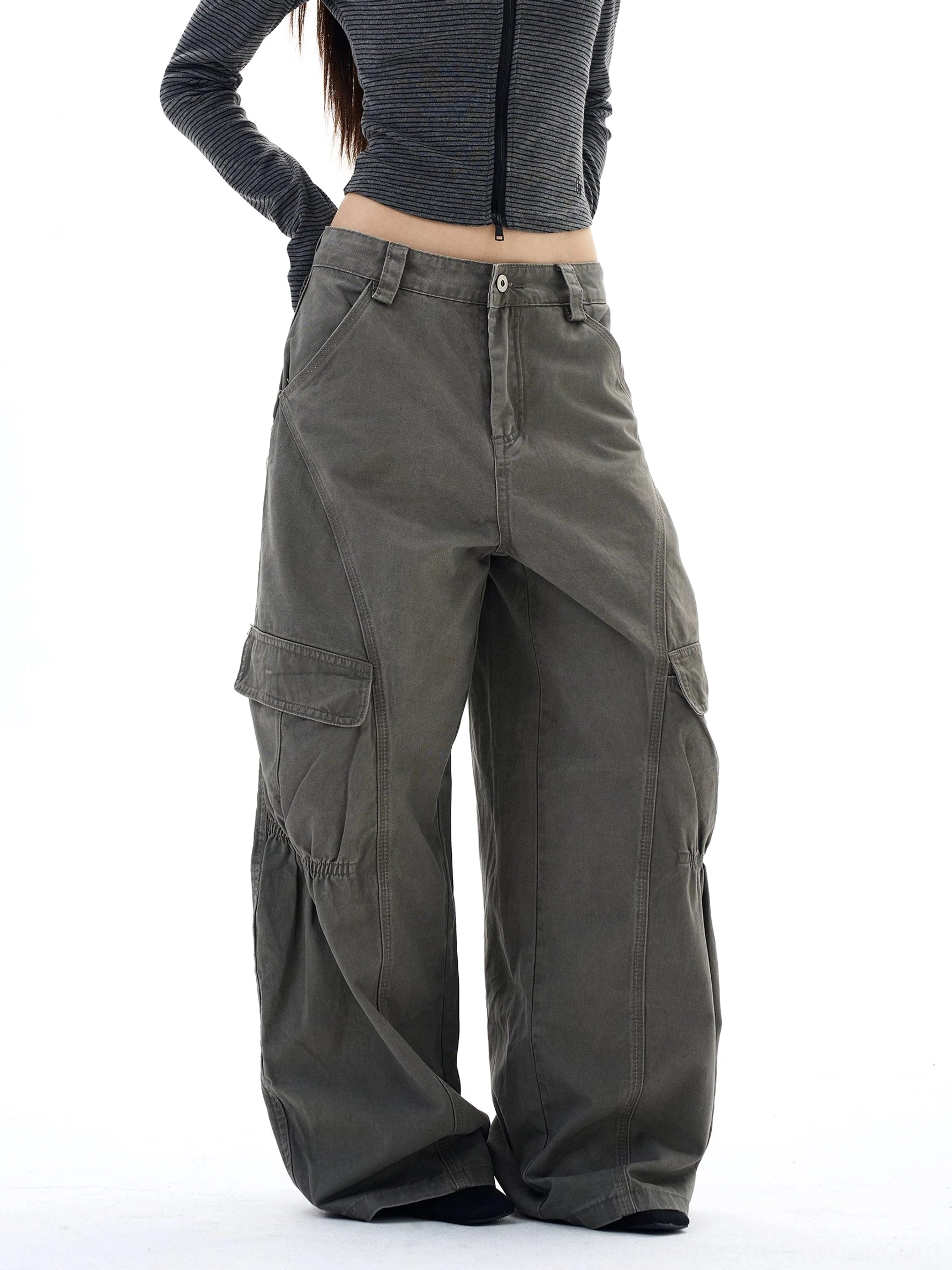 Right side view of washed gray-green utility cargo pants featuring asymmetrical panel stitching and gathered knee construction