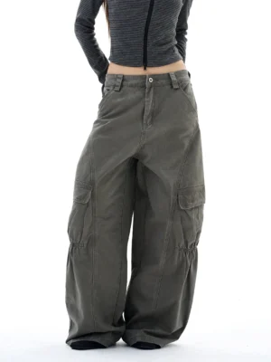 Front three-quarter view of washed gray-green wide-leg streetwear cargo pants with oversized utility pockets and gathered knee detailing