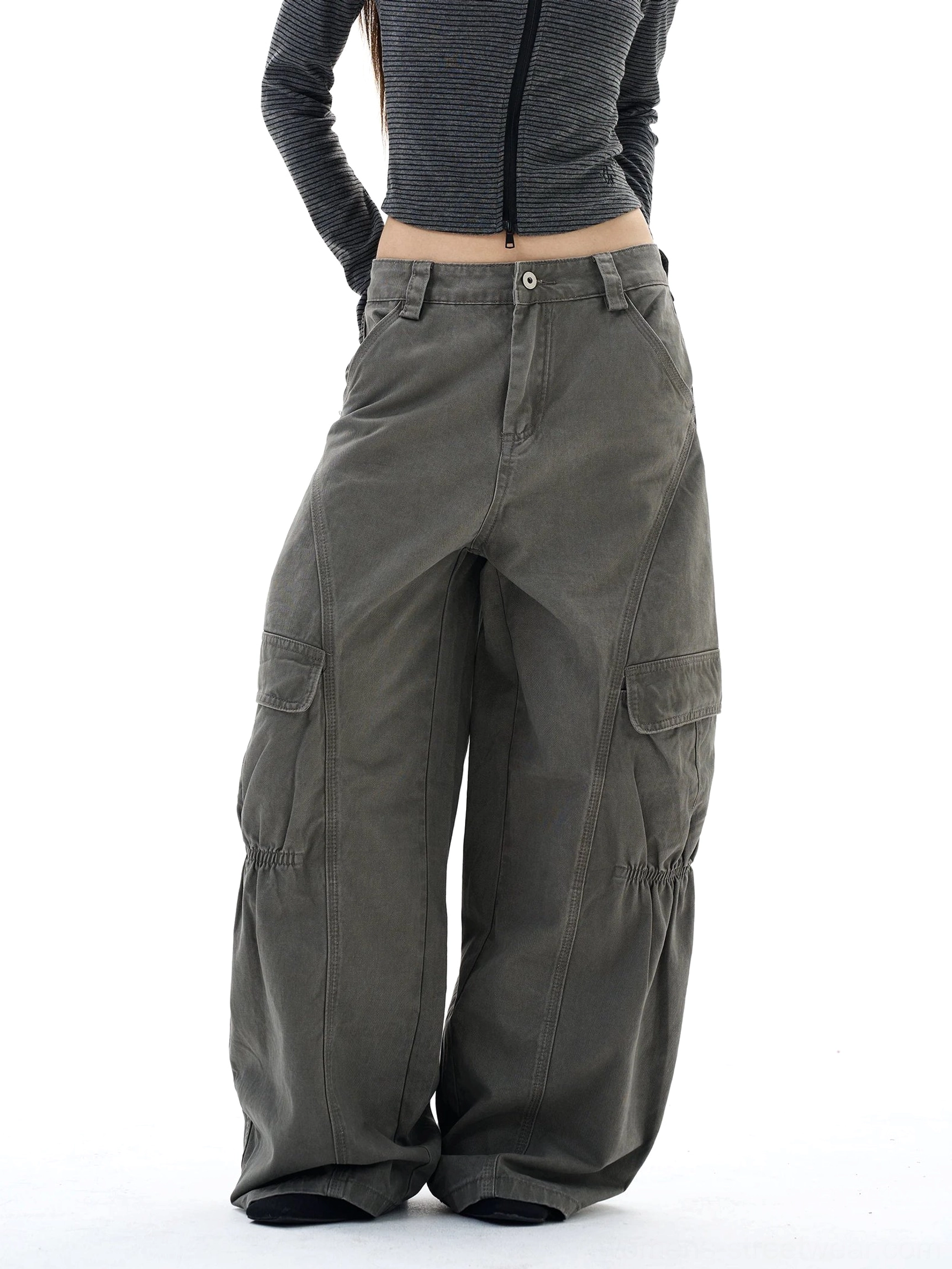 Front three-quarter view of washed gray-green wide-leg streetwear cargo pants with oversized utility pockets and gathered knee detailing