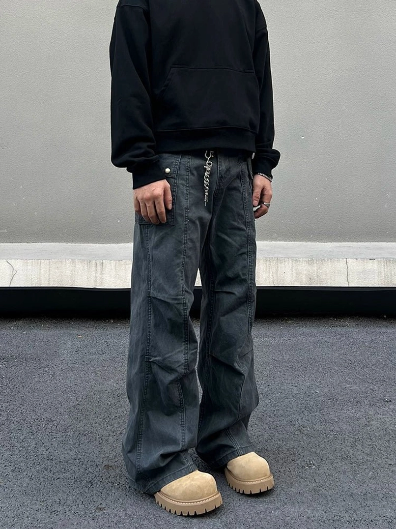 Front view of washed gray wide-leg streetwear cargo pants styled with a black hoodie and chunky tan work boots in an urban setting