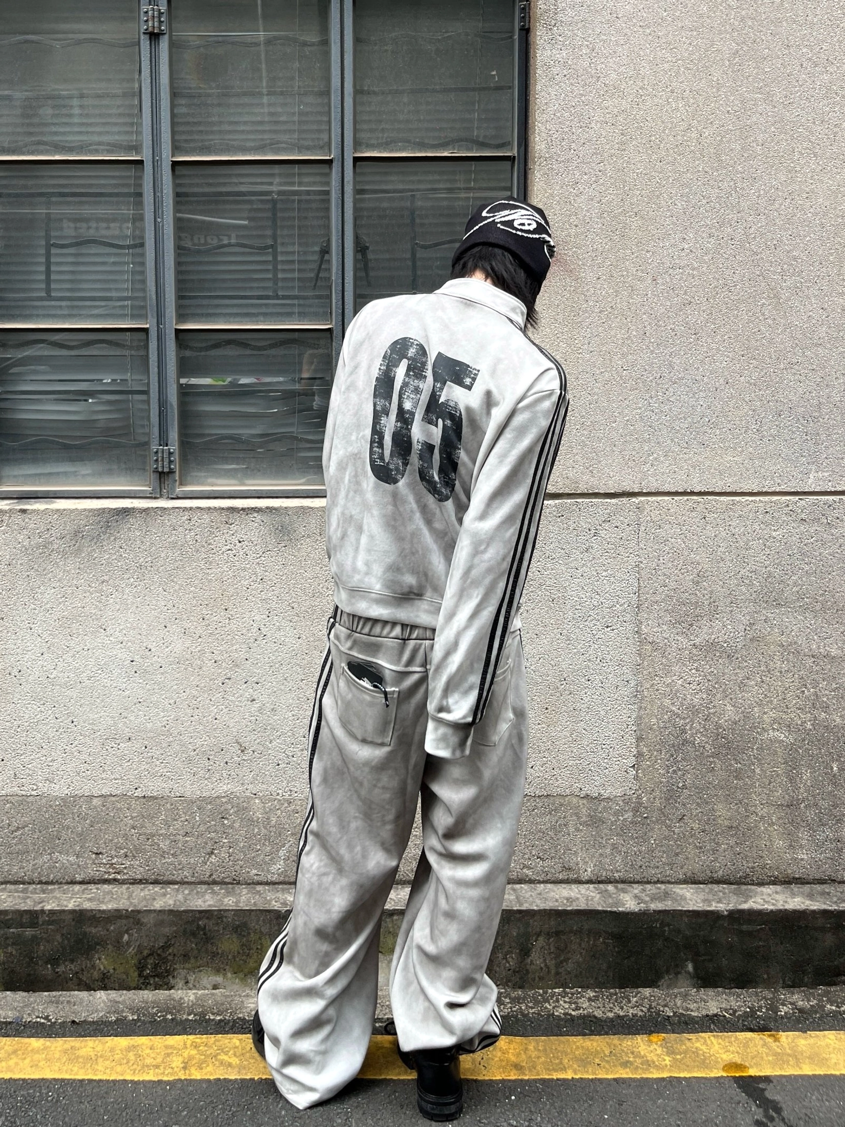 Rear view of a washed white grunge track jacket showing the large weathered 05 back print and black stripe details
