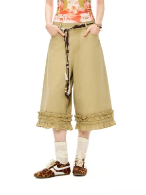 Front detail of washed khaki ruffle hem wide-leg culottes styled with a printed tank top, rolled socks, and leopard print sneakers
