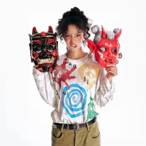 Multicolor washed tribal graphic oversized long sleeve tee front view on female model holding folk masks