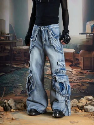 Light wash vintage blue multi-pocket cargo jeans shown from a low front angle with an ultra-wide leg, oversized side pockets, layered utility details, and ankle zippers in a post-apocalyptic streetwear setting