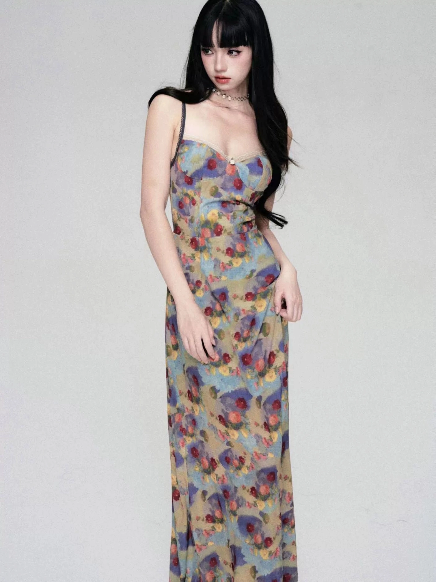 Woman wearing a watercolor floral slip maxi dress with sweetheart neckline, thin spaghetti straps, slim full-length silhouette, and vintage Korean streetwear styling in a minimalist studio