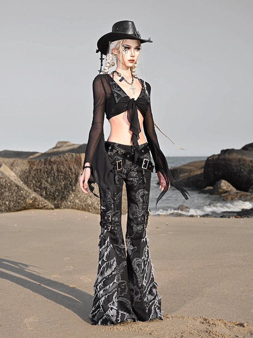 Side three quarter view of western goth dragon flare jeans with frayed denim legs, buckle strap details, and contemporary alternative streetwear styling