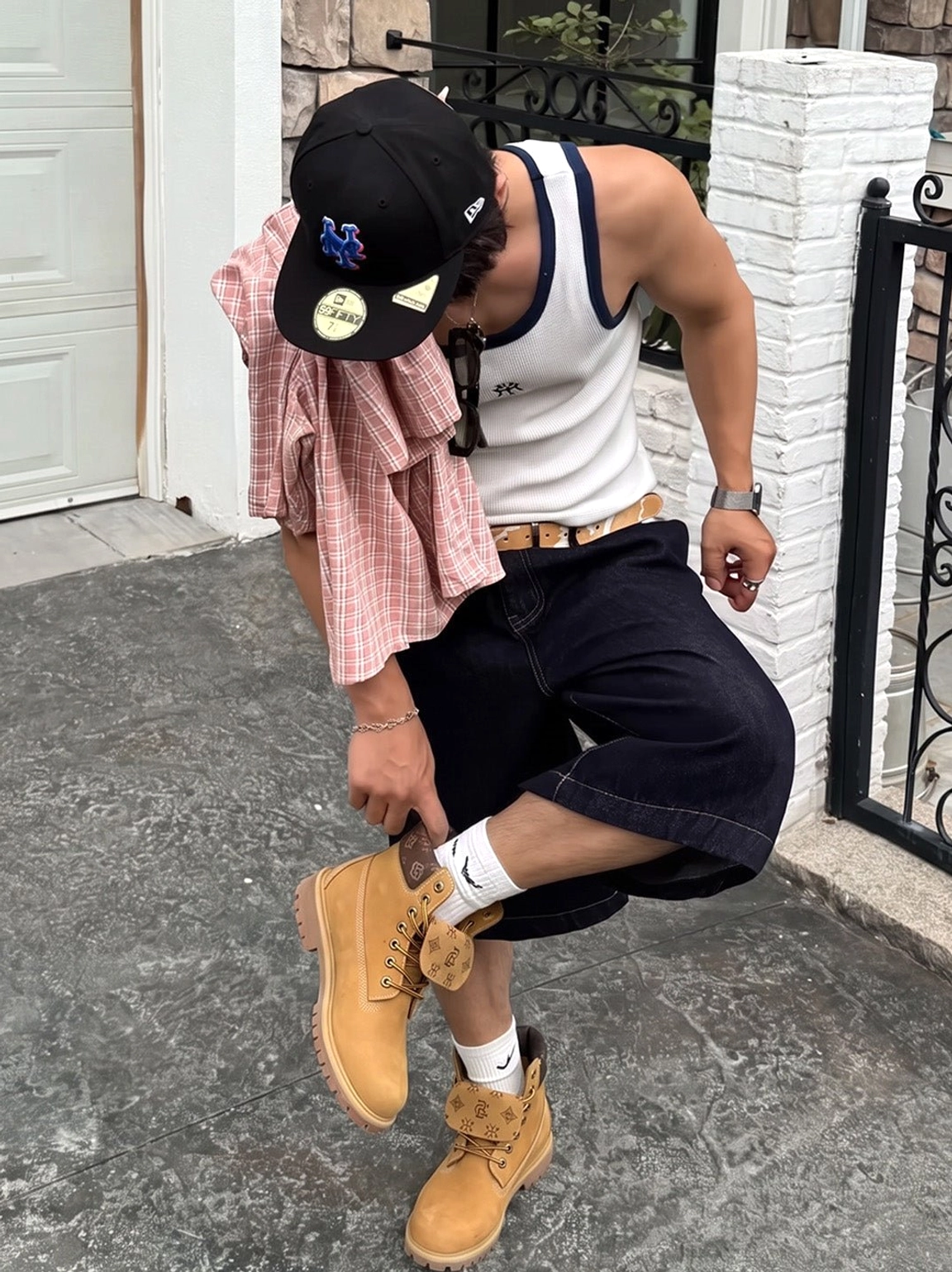 Close streetwear styling view of male model adjusting wheat contrast-stitch lug sole lace-up work boots
