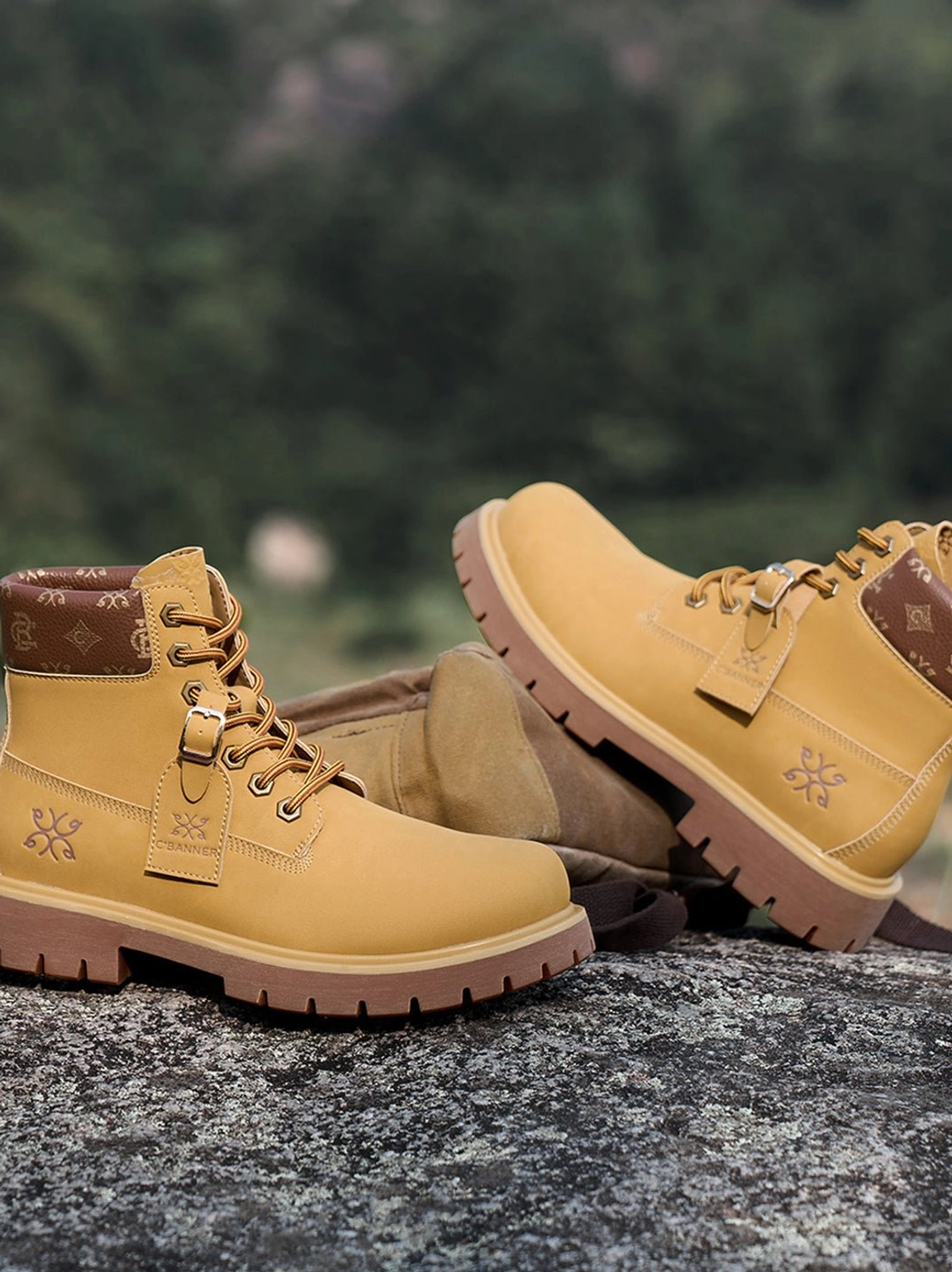 Multiple pairs of wheat contrast-stitch lug sole work boots arranged in an outdoor mountain setting