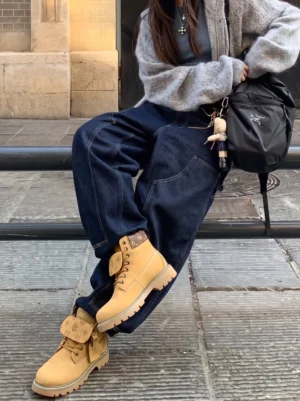Female model wearing wheat contrast-stitch lug sole work boots with a casual streetwear outfit on stone steps