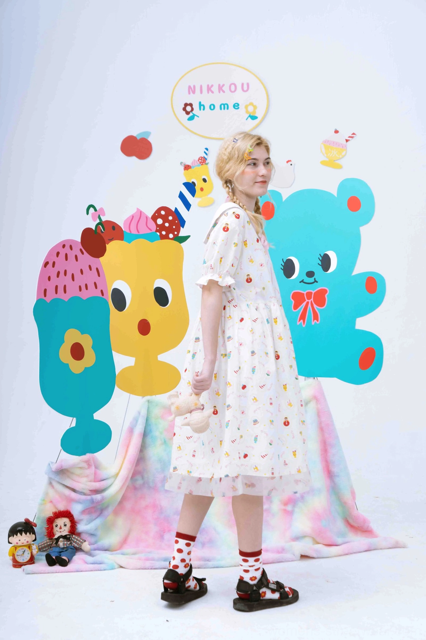 Side view of a whimsical printed sailor collar babydoll midi dress styled with red polka dot socks and black platform sandals