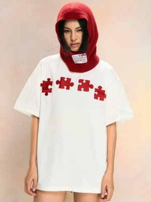 White 3D puzzle embroidered oversized streetwear tee worn by female model in a red knit balaclava front view