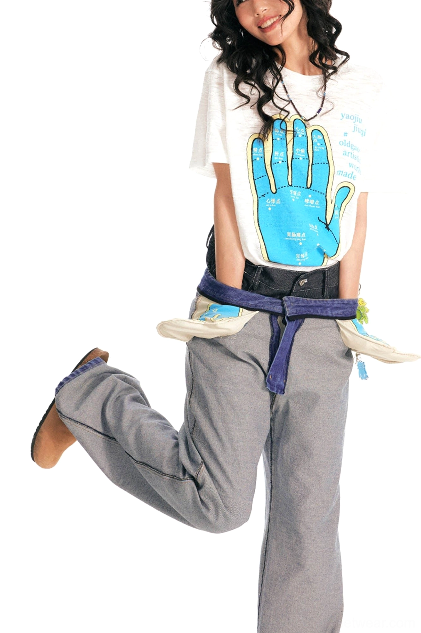 Dynamic female streetwear outfit featuring white acupuncture hand map t-shirt and low-rise grey pants