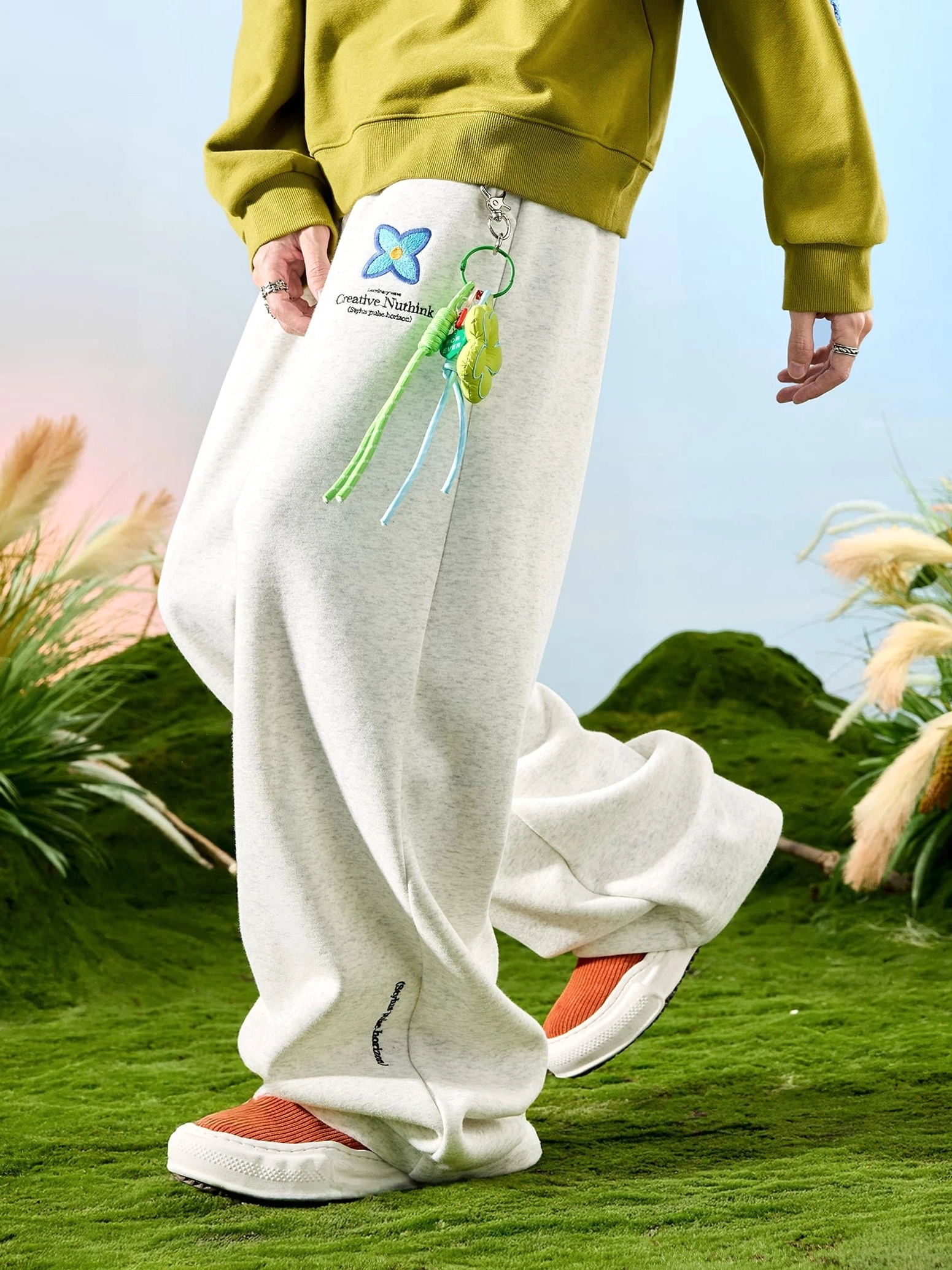 White ash embroidered floral drawstring wide-leg sweatpants with colorful tassel charm shown in a dynamic side view