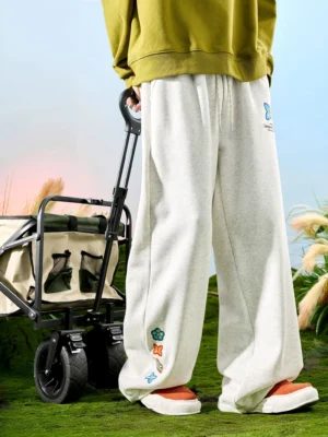 White ash embroidered floral wide-leg streetwear sweatpants with drawstring waist worn outdoors in a relaxed front view
