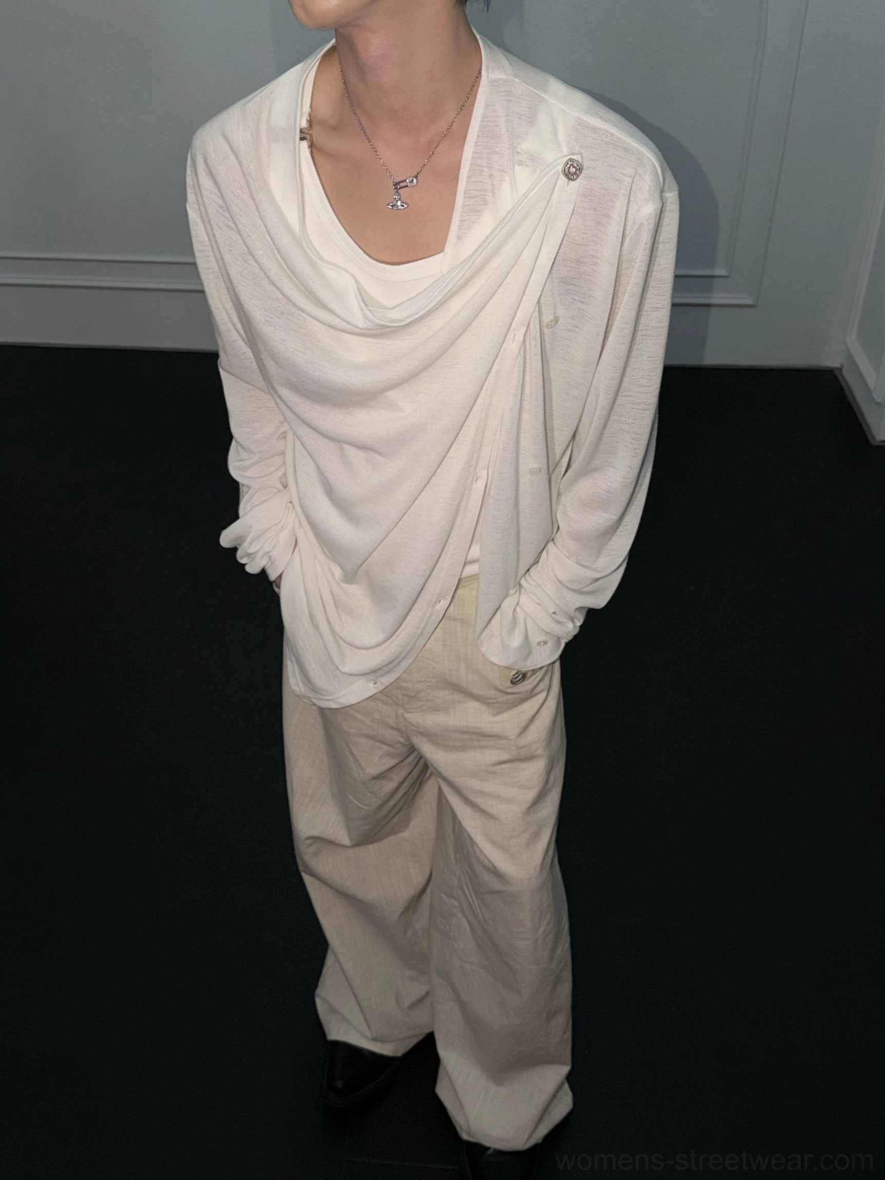 White asymmetric draped long-sleeve top styled with beige wide-leg trousers and black leather shoes in a minimalist outfit