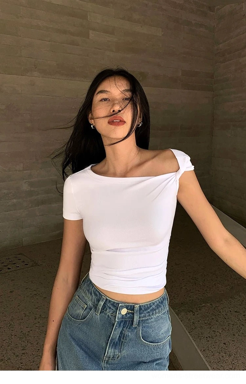 White asymmetric off-shoulder cropped tee with a slim waist-hugging fit styled with blue denim pants