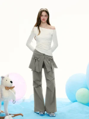 Full-body styling view of a white asymmetrical off-shoulder streetwear top paired with grey wide-leg bow detail pants in a contemporary Korean fashion outfit