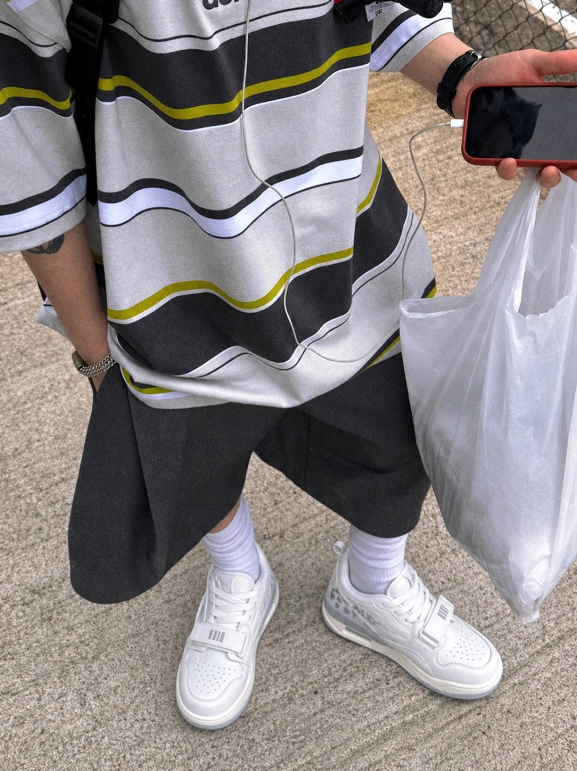 White low-top basketball-inspired casual sneakers worn with wide-leg black shorts, white socks, and a relaxed streetwear outfit