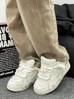Model wearing white distressed bat panel platform sneakers with thick rope laces and sculpted skate soles in a low front streetwear outfit view