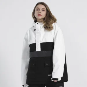 Female model wearing a white and black two-tone colorblock snow anorak jacket with attached hood, half-zip front, flap cargo pockets, and contrast waist detail in a studio setting