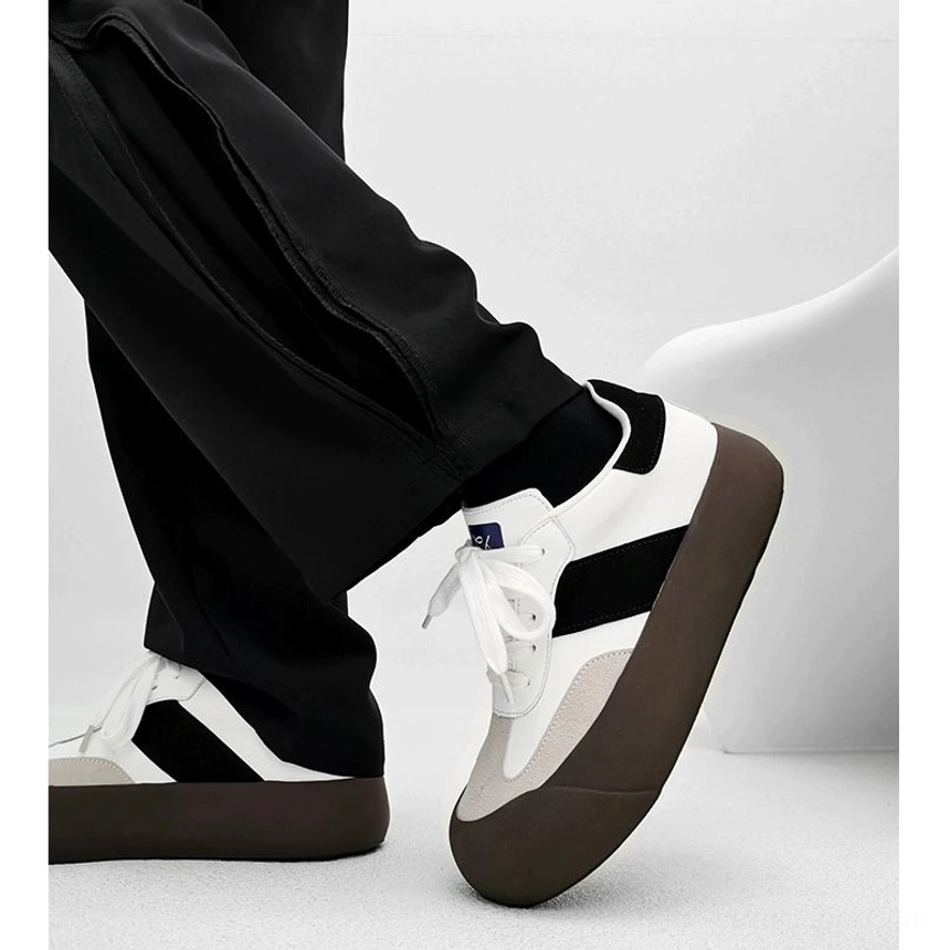 White and black vintage chunky sneakers with dark brown rubber outsole worn with black cargo pants in a casual urban outfit