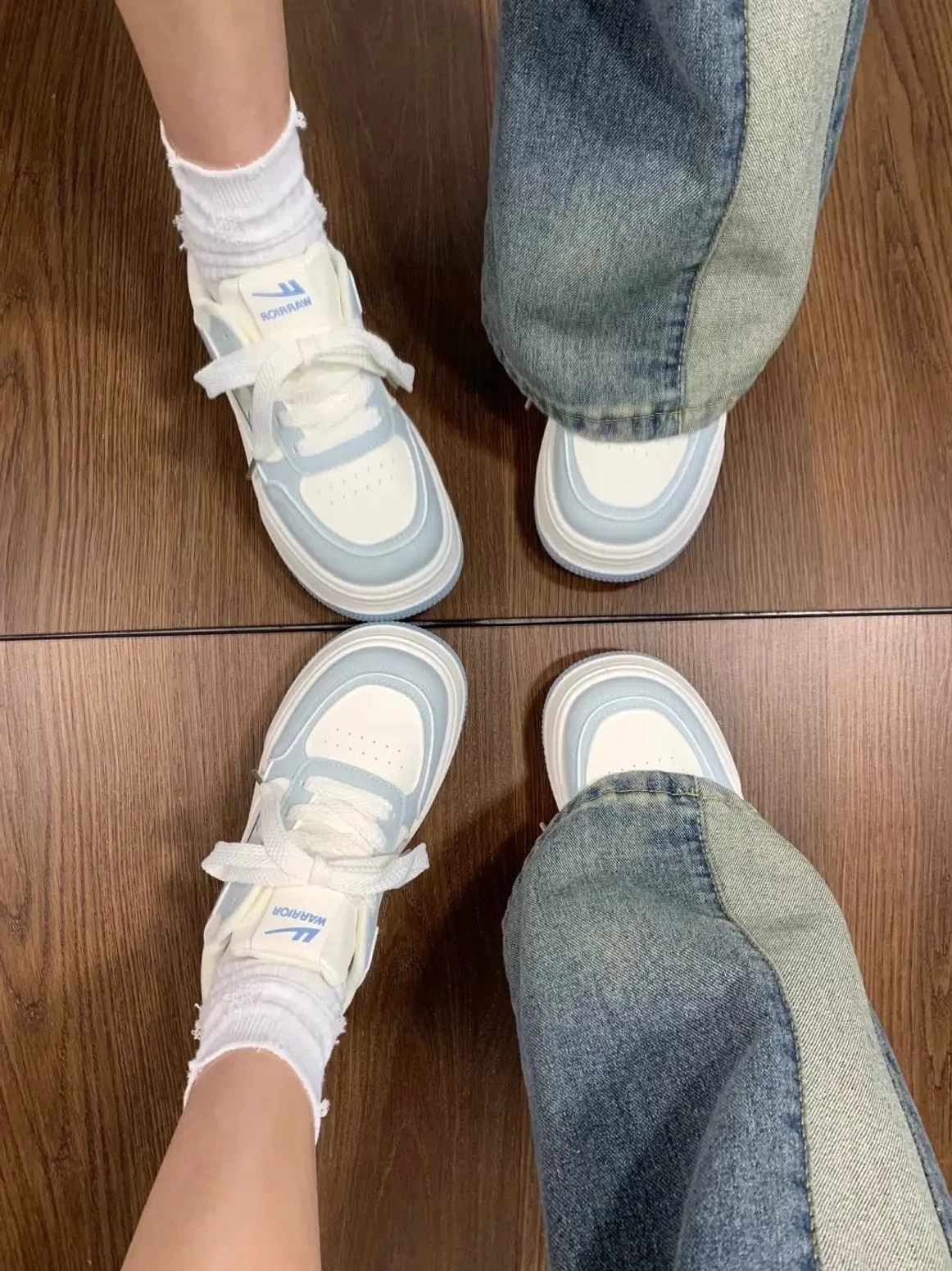 Top view of matching white and light blue chunky platform sneakers styled with patchwork flare jeans