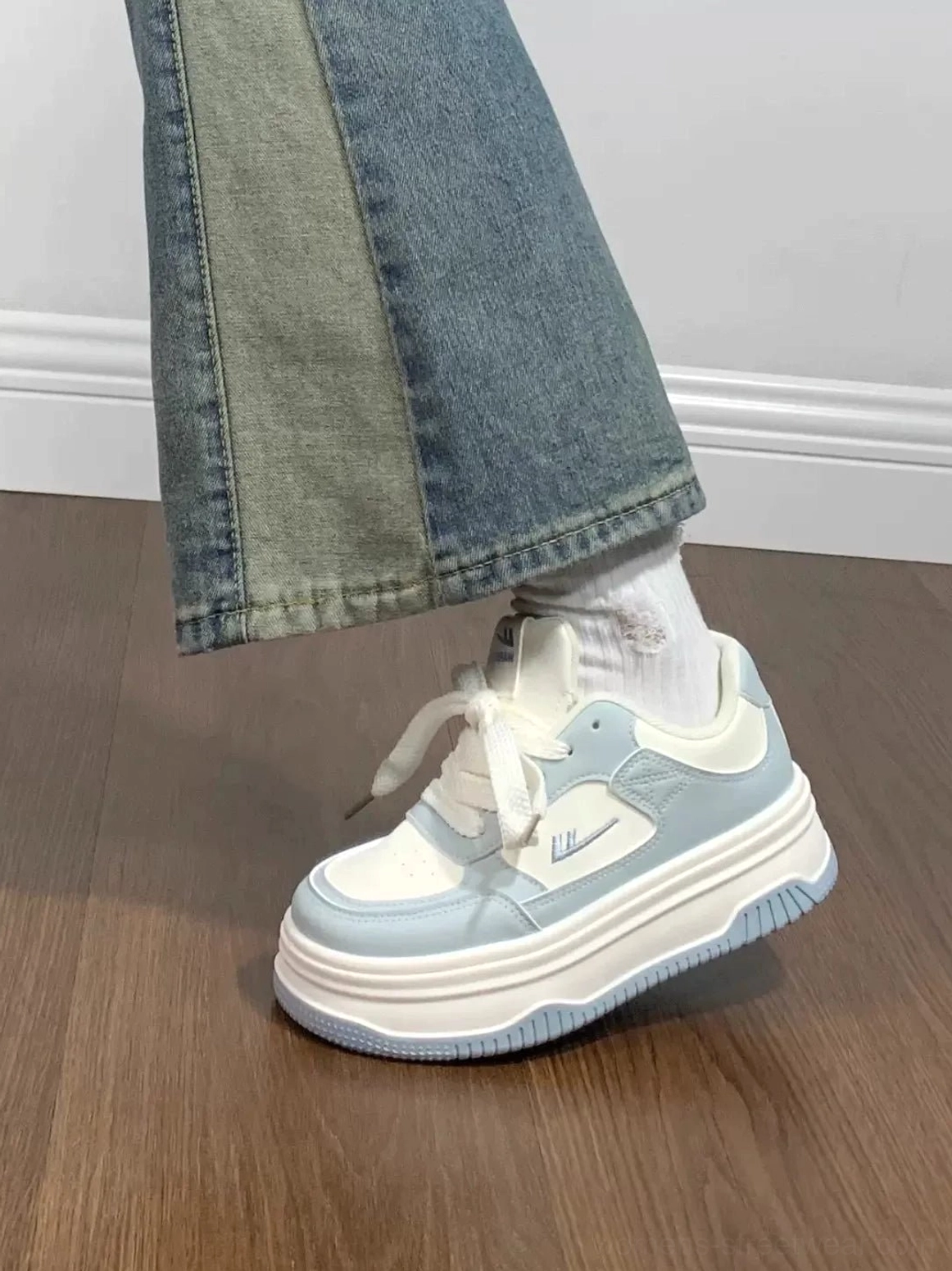 Close-up of a white and light blue low-top platform sneaker with smooth panels and contrast blue sole