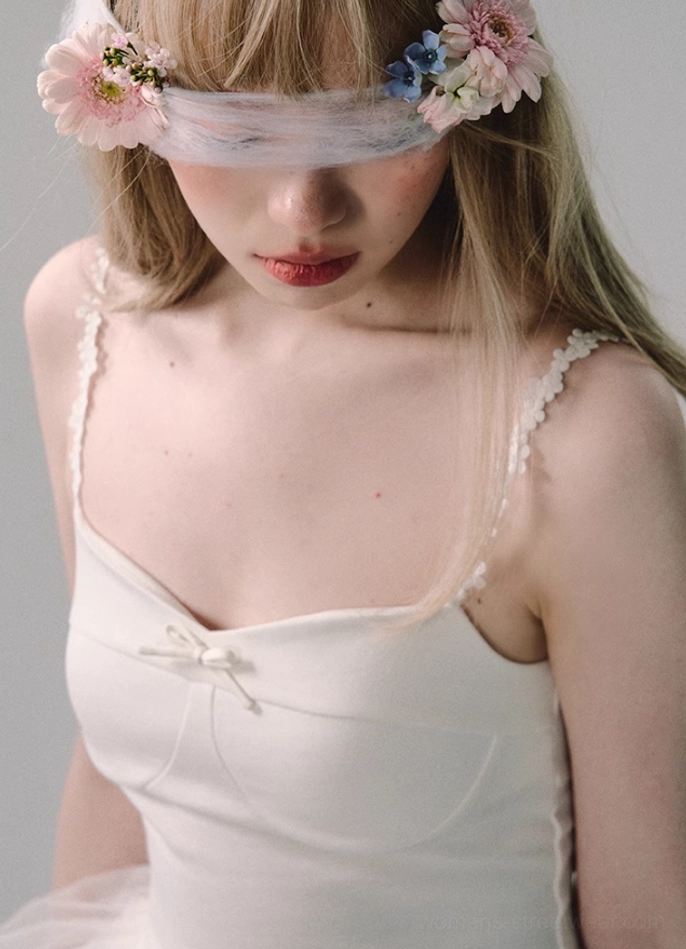 Close-up of white bridal tulle gown neckline with satin bow, padded bust cups, delicate lace spaghetti straps, and romantic detailing