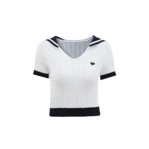 Flat lay front view of a cream white cropped cable knit sailor collar top showing the V-shaped collar, navy contrast trim, short sleeves, and embroidered chest badge