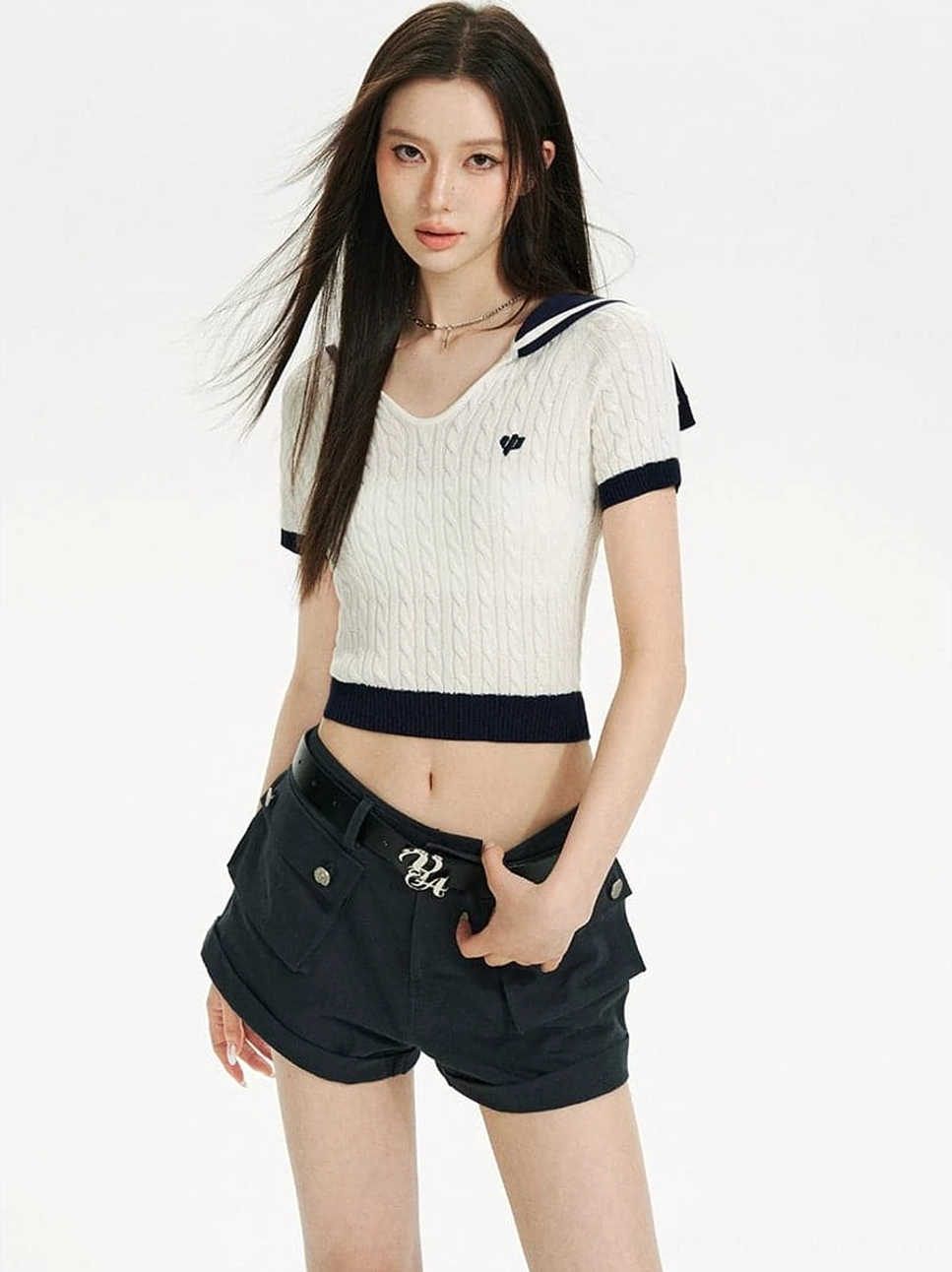 Full front view of a cream white cable knit cropped sailor collar top with navy blue trim, embroidered chest detail, and fitted short-sleeve silhouette styled with navy cargo shorts