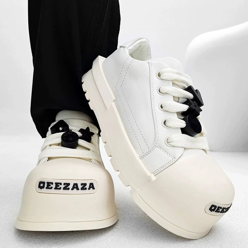 White chunky platform lace charm sneakers side close-up with black laces oversized toe and thick rubber midsole