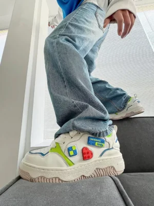 Model wearing white chunky platform skate sneakers with colorful building block details styled with baggy light blue jeans in a casual streetwear outfit