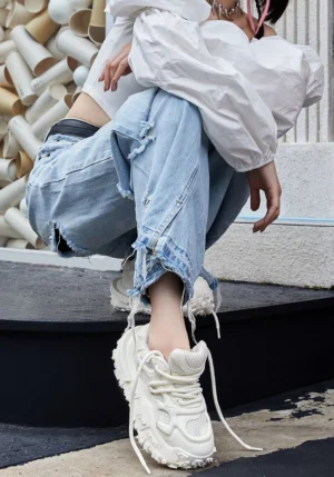 White chunky platform sneakers worn with ripped wide-leg jeans and an off-shoulder blouse in a casual Seoul-inspired streetwear outfit