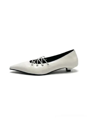 White corset-lace pointed ballet flats with glossy leather-look upper, slim low heel, sharp toe, and crisscross instep lacing shown in side profile