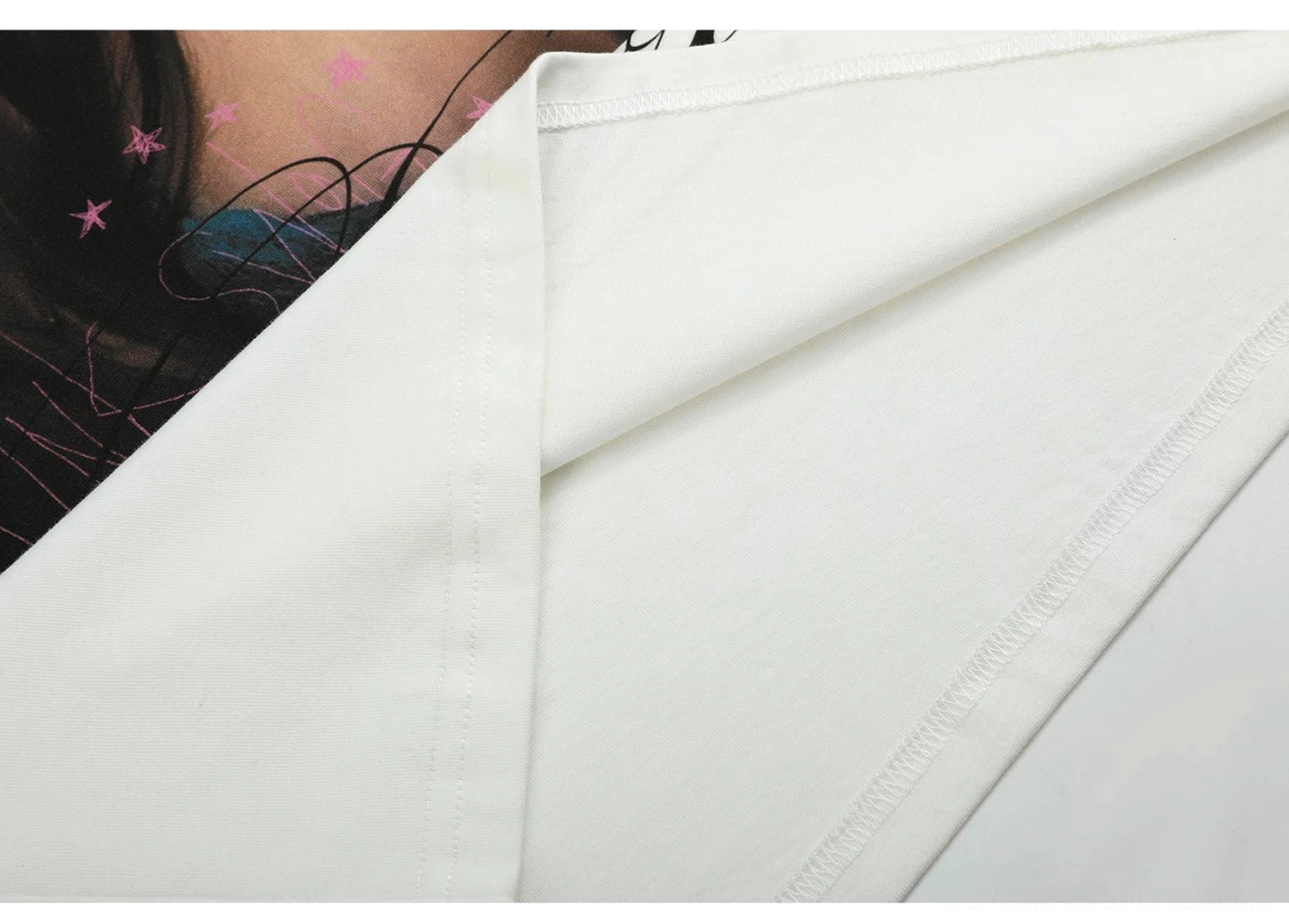 White cotton graphic T-shirt side seam detail showing neat coverstitch construction and smooth finished fabric